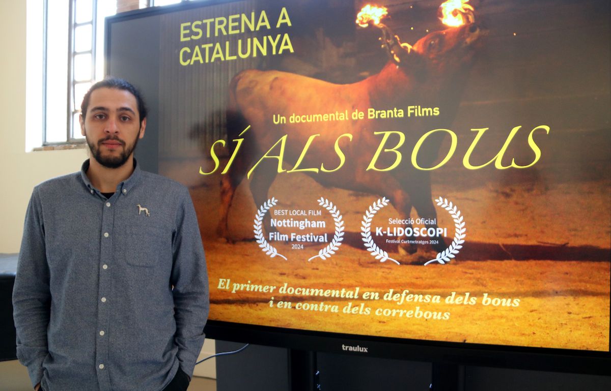 El director al costat del cartell del documental.